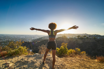 athletic african american woman celebrating reaching top of runyon canyon with arms open - Powered by Adobe