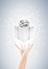 hand with silver gift box and magic twinkles