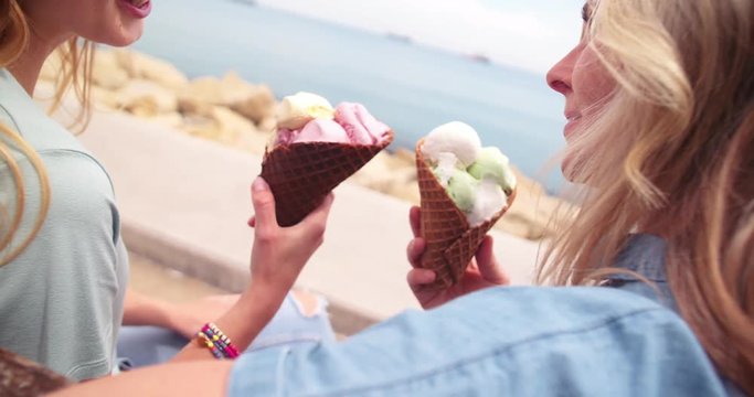 Mother And Daughter Eating Ice Cream And Talking At Seaside