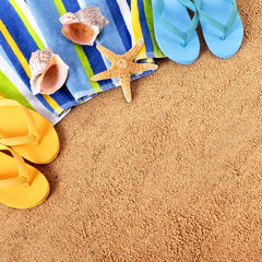 Fototapeta na wymiar Beach sand background with towel starfish and flip flops square format summer holiday vacation sunbathing scene photo