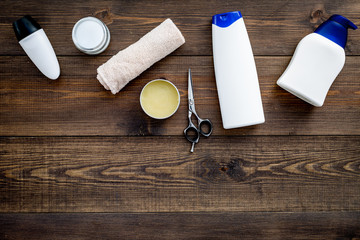 Cosmetics for men's hair. Bottles with shampoo and gel, tools for brushing on dark wooden background top view copy space