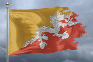 Bhutan Flag with torn edges in front of a stormy sky