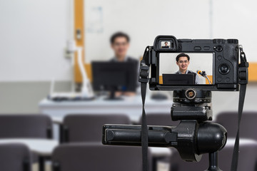 Professional digital Mirrorless camera on the tripod recording video blog of Asian teacher in the...