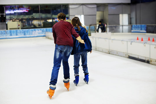 Teenage couple holding hands and ice skating together