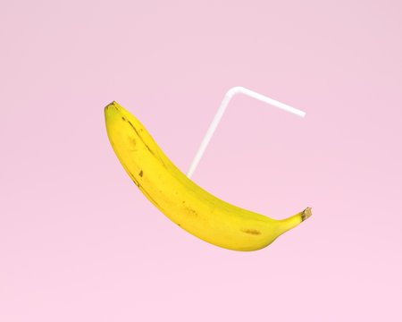 Banana, Juice with straw on pink color pastel background. minimal fruit concept. Idea creative foods and drinks that are typically enjoyed at summer times and summer festivals around the world