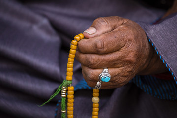 Old Tibetan woman holding buddhist rosary in Hemis monastery, Ladakh, India. Hand and rosary, close up - Powered by Adobe