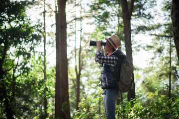 Naklejka na ściany i meble Woman with Binoculars walking in the forest