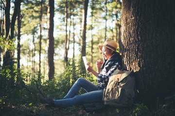 young woman listening to music from smartphone under the tree in the garden.