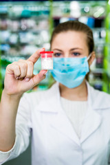 Woman apothecary looking at container with tablets in drugstore