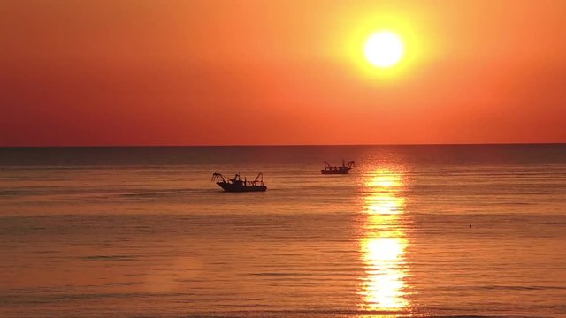 Time lapse fishing boats pull their nets at the sunrise. Adriatic cost. Emilia Romagna. Italy