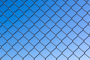 Fototapeta na wymiar Close up of chain wire fence against blue sky