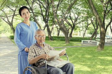 Cheerful nurse with elderly man in the park