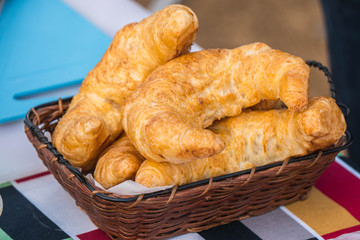 fresh croissants in a basket on a wooden table