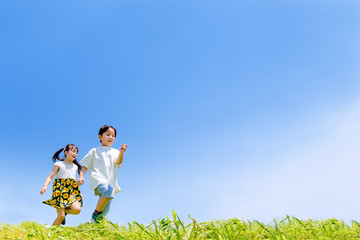 緑の丘を走る元気な男の子と女の子の2人