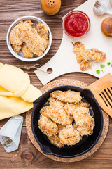 Homemade nuggets from chicken in a iron frying pan. Top view