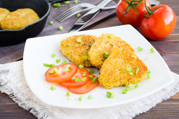 Crispy hash browns and tomatoes on a plate on a wooden table