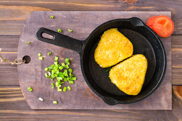 Crispy hash browns in a iron pan on a wooden table. Top view