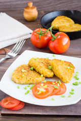 Crispy hash browns and tomatoes on a plate on a wooden table
