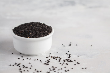 Fototapeta na wymiar Nigella sativa or Black cumin in white bowl on white background, copy space