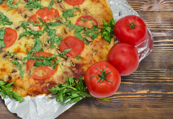 Fragment of cooked pizza and fresh tomatoes on a foil