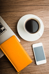 Office desk with laptop computer, planner, mobile smartphone and coffee cup.