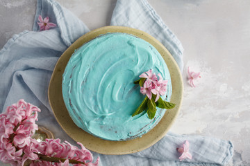 Blue stylish cake with flowers and mint on wooden box. Copy space, top view, flat lay food