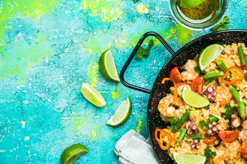 Seafood paella in pan served with beer and lime