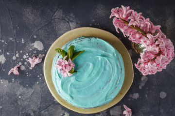 Blue stylish cake with flowers and mint. Copy space, dark background, flat lay food