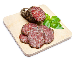 Dried organic salami sausage covered with pepper on wooden serving board