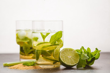Brazilian traditional caipirinha with lime, sugar and mint in glasses. White background, dark table, copy space.