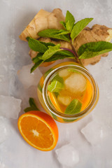 Ginger orange ice tea with mint in a glass jar, white background, copy space, top view. Summer refreshing drink concept.