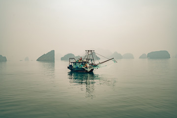 a solitary fishing boat in Ha Long Bay Vietnam