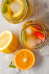 Fruit ice tea and ginger herbal ice tea with mint in glass jars, white background, top view copy space. Summer refreshing drink concept.