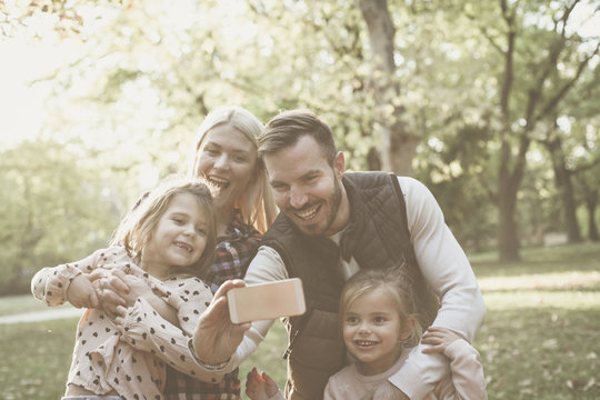 Smiling father taking self picture of family in nature.