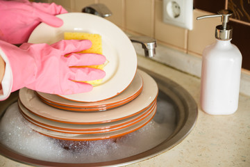 Hands doing the dishes in the sink