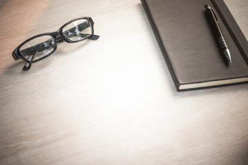 Fototapeta premium Wood office desk table with notebook and pen,cup of coffee.Top view with copy space.