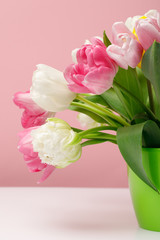 Bouquet of spring tulips in vase on pink background