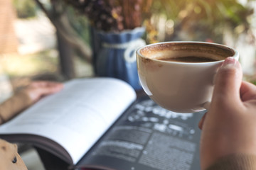 Closeup image of a woman reading book and drinking coffee in cafe