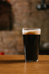 close-up view of glass with delicious dark beer on table in pub