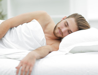 smiling man sleeping on a comfortable bed.