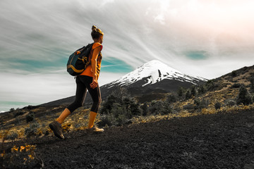 Hiker walks on the slope of volcano. Woman enjoys the trail with views of the volcano of Osorno,...