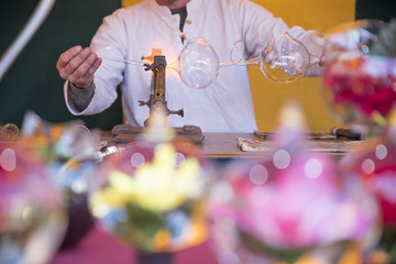 Artesania del vidrio habil y perfecta   trabajando con soplete en una feria medieval popular a la vista del publico asistente asombrado ante la habgilidad del artistaa la fiesta