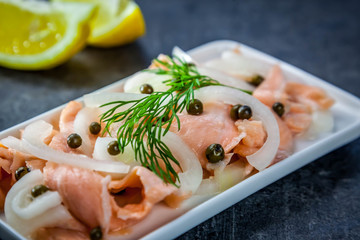Slices of raw salmon marinated in lemon with green pepper and onion