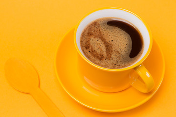 yellow cup with a drink of coffee with foam on a yellow background