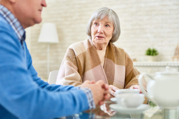 Portrait two senior friends enjoying tea time meeting at home and sharing memories, focus on nice elderly lady, copy space