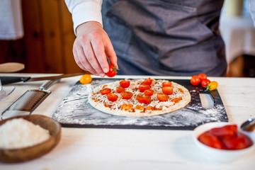 Obraz na płótnie Canvas closeup hands of chef making fresh homemade traditional italian pizza. wallpaper for pizzeria and cooking food concept