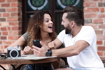 Portrait of a young  couple sitting down at a cafe terrace
