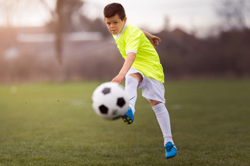 Boy kicking football on the sports field