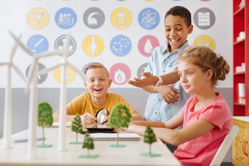 Perfect team spirit. Joyful teenage students joking and laughing while discussing an ecology project related to the alternative sources of energy
