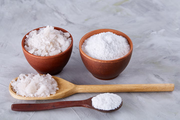 Fototapeta na wymiar Composition of sea salt in ceramic bowl and spoon for cooking or spa on white background, top view, selective focus